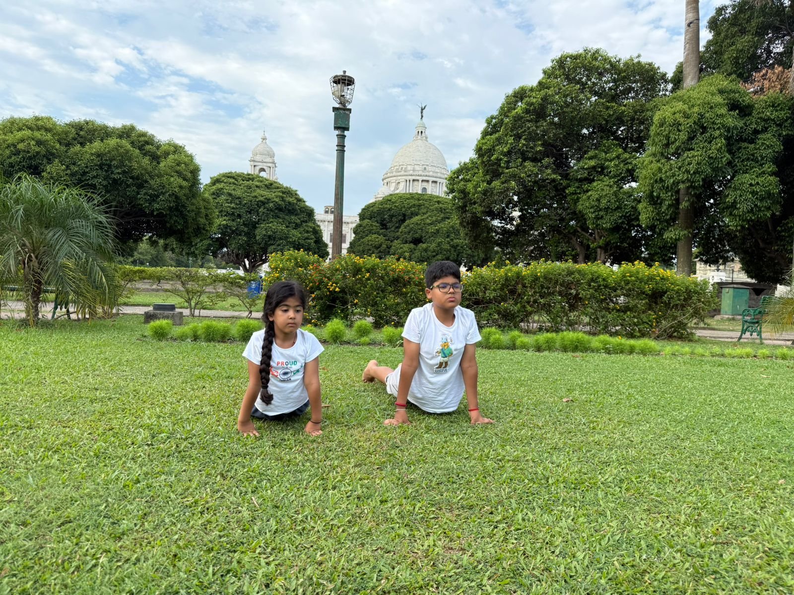 Praney and Kashvi practising yoga on lush green lawns with the majestic Victoria Memorial in the background